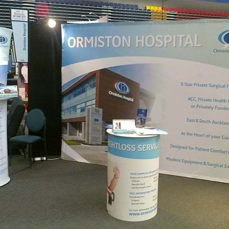 Simple booth display with backdrop, round counter and standee - Displays2Go